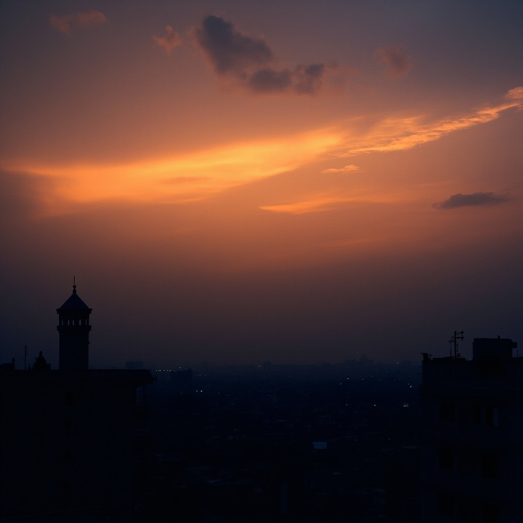 An aerial view of Tehran at dusk with the silhouette of a mosque minaret against an orange sky