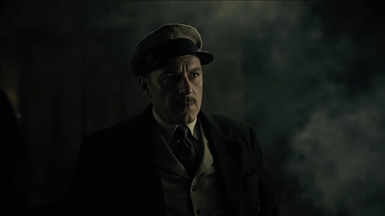 Tim Roth as Nazi agent Beckett, sneering aboard a train loaded with counterfeit banknotes