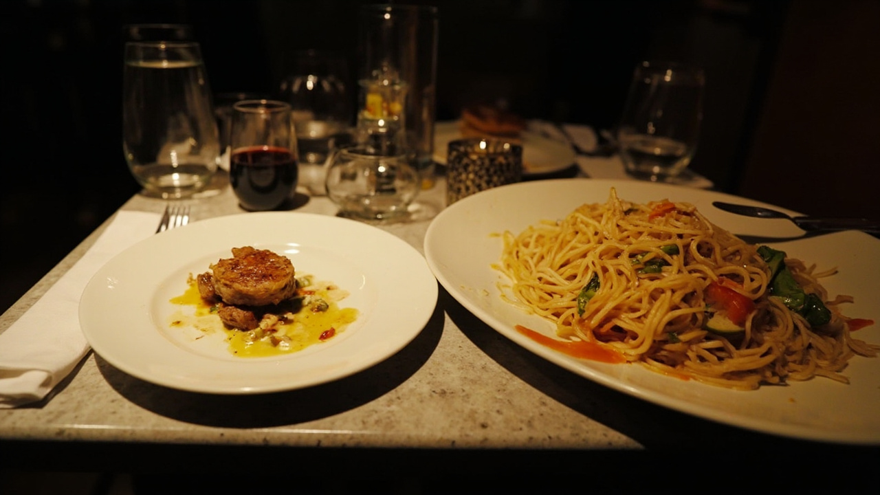 A restaurant table with a small, elegant high-protein dish alongside a traditional oversized pasta plate, both under warm overhead lighting