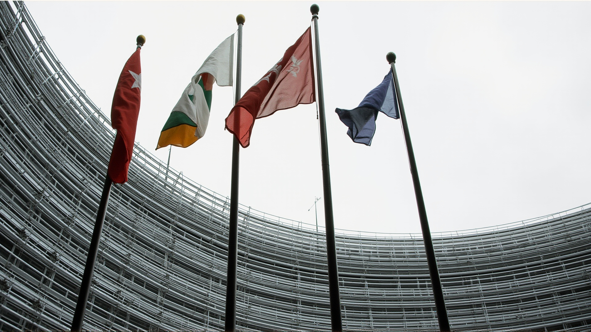 The European Council building in Brussels, flags of member states, overcast sky, institutional gravitas