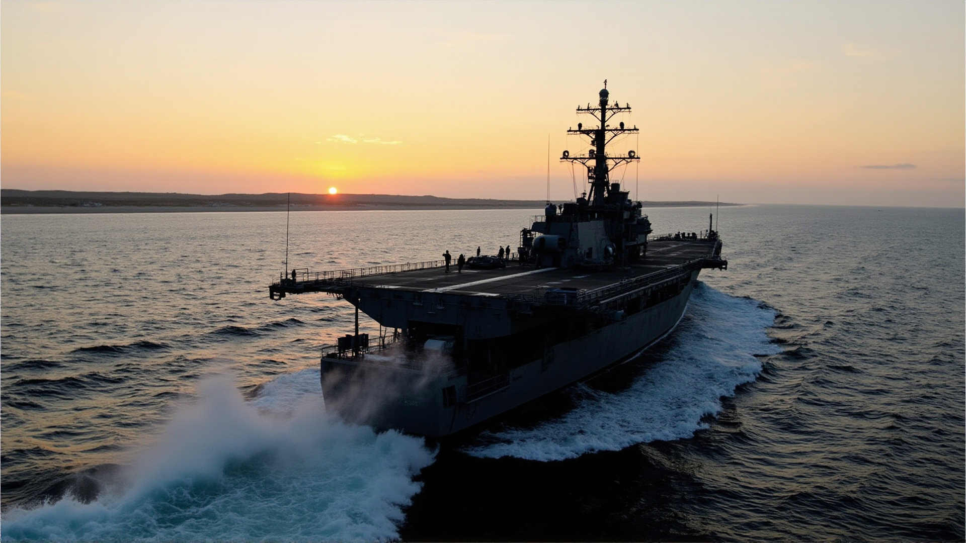 A naval vessel cutting through Gulf waters at dawn, flight deck visible, crew on deck, desert coastline in the far distance