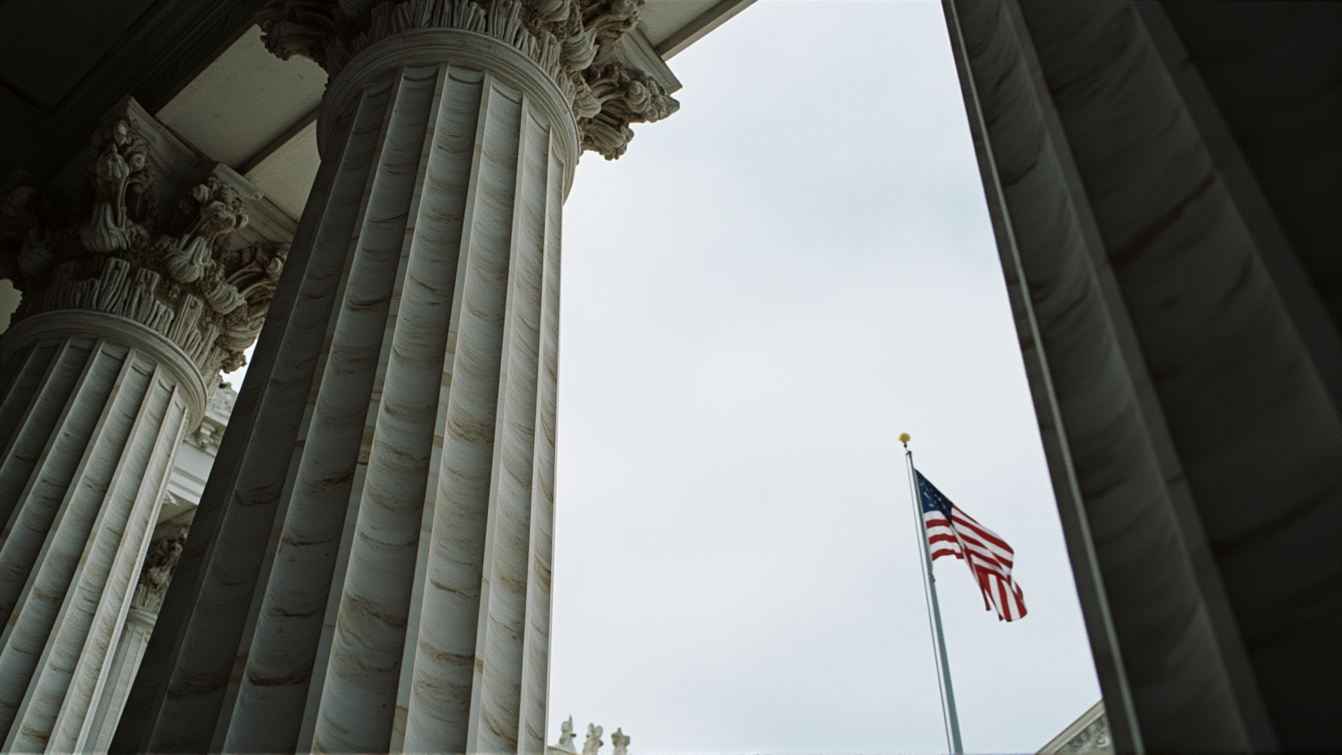 The Supreme Court building columns, shot from below, American flag, stark contrast between marble and sky
