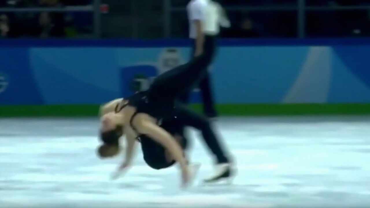 Figure skater after falling, head bowed, ice visible beneath, arena lights above