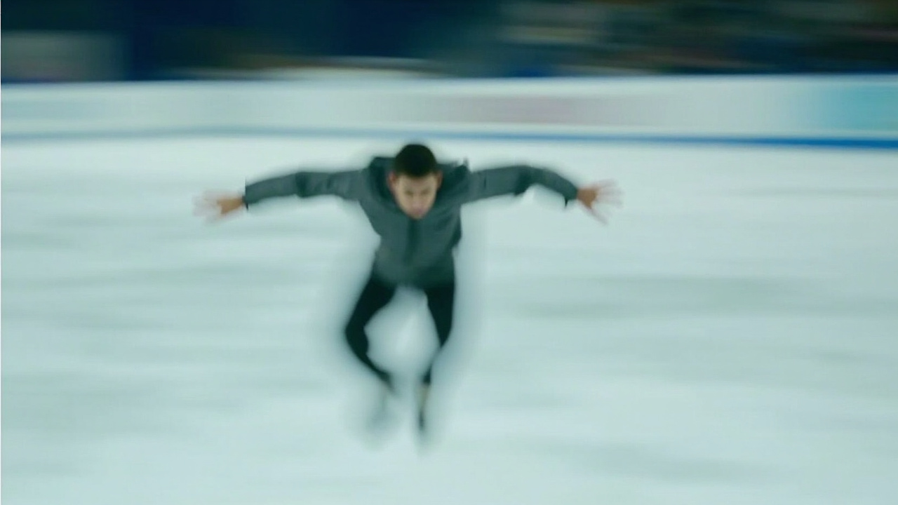 Figure skater in mid-air during jump, arms extended, sharp focus, motion blur on ice
