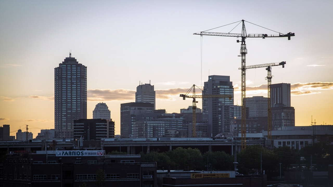 Kansas City skyline with construction cranes, suggesting infrastructure preparation, evening light