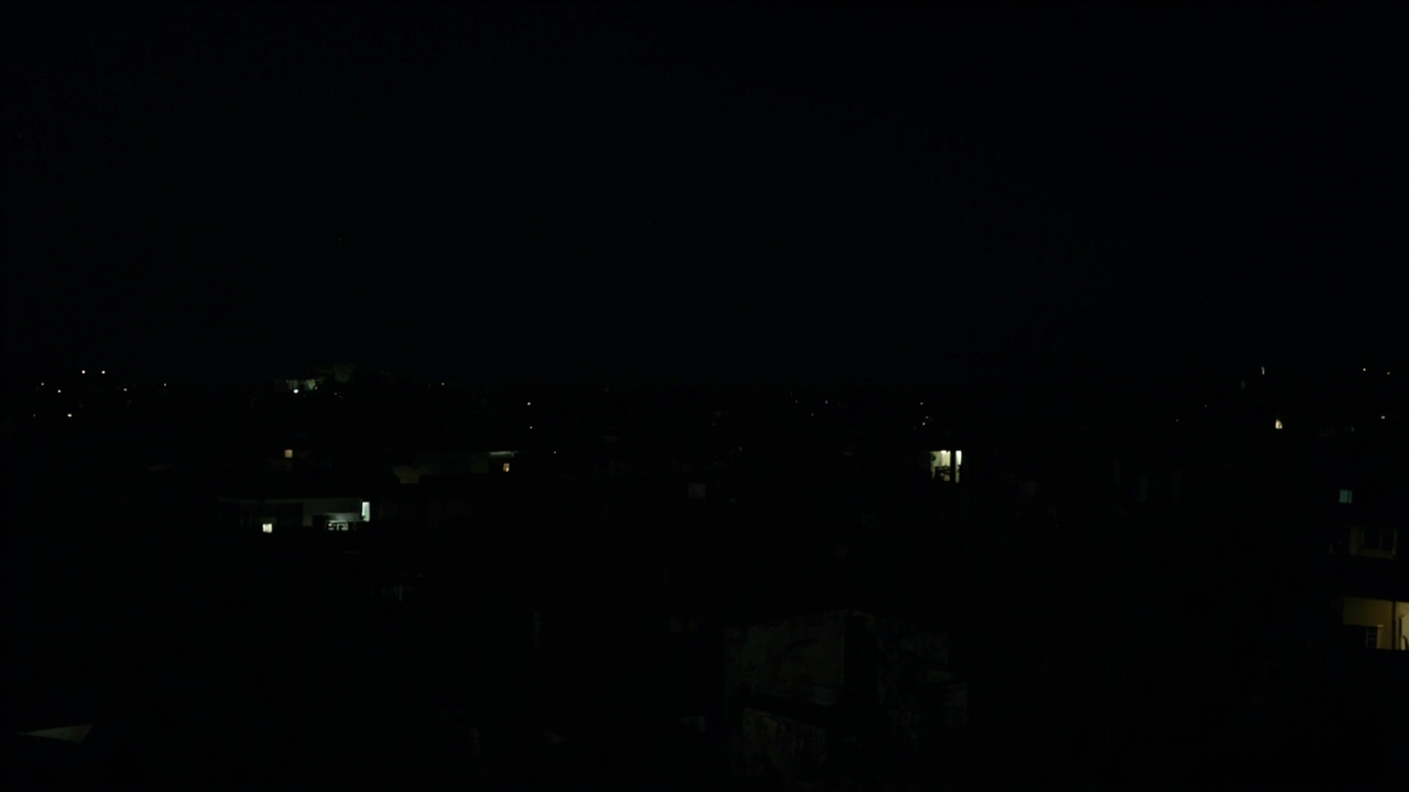 An aerial view of a darkened Havana neighborhood at night with only a few scattered generator-powered lights visible