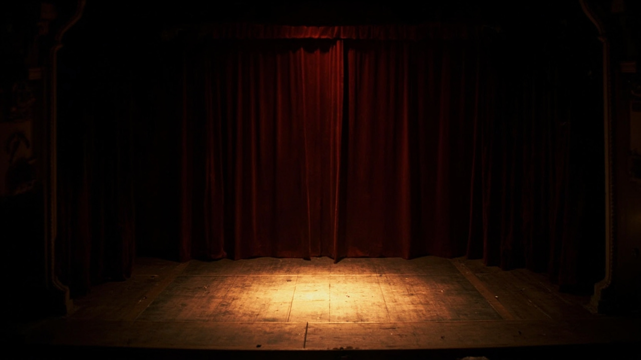 Empty classic theater stage in Istanbul, velvet curtains half-drawn, a single spotlight illuminating the center of the stage, wooden floors worn smooth by decades of use