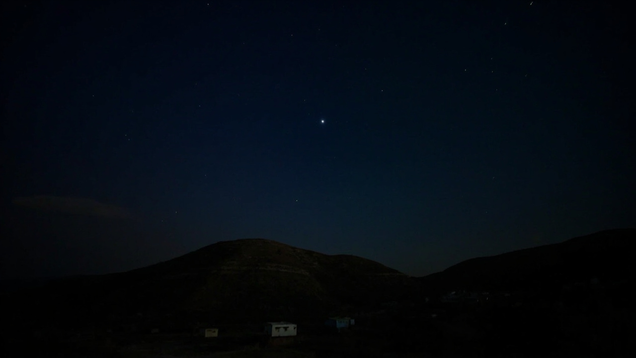 Night sky with rocket trails over hilly terrain