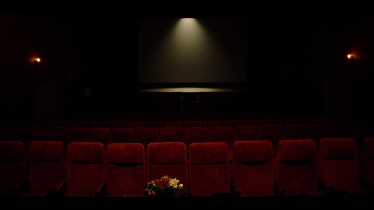 An empty European cinema with a single spotlight and flowers on a seat