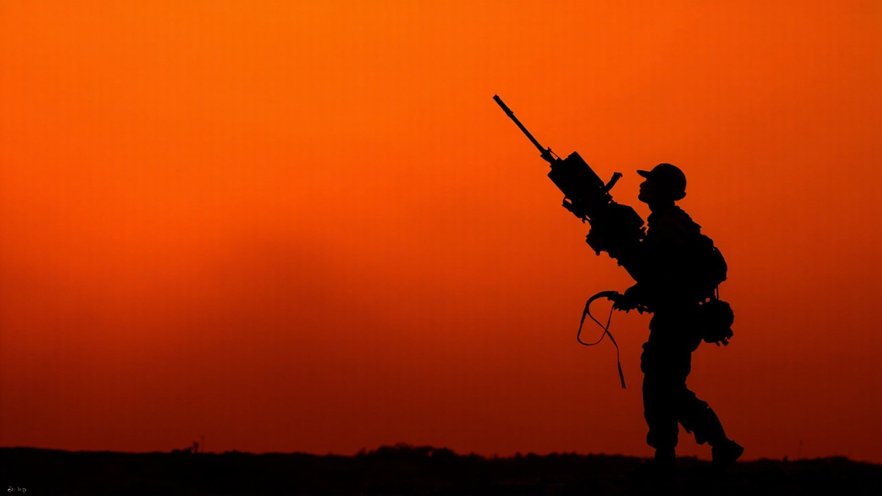 Silhouette of a soldier holding a shoulder-fired missile launcher against an orange sky