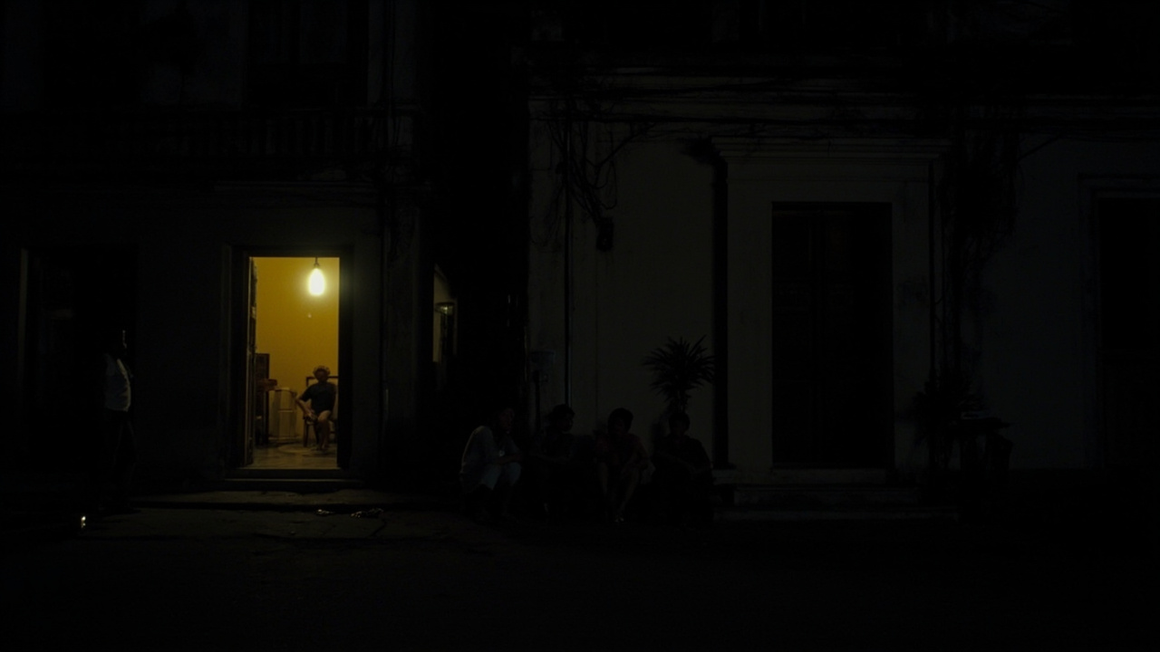 Darkened Havana street at night with a single generator light illuminating a doorway