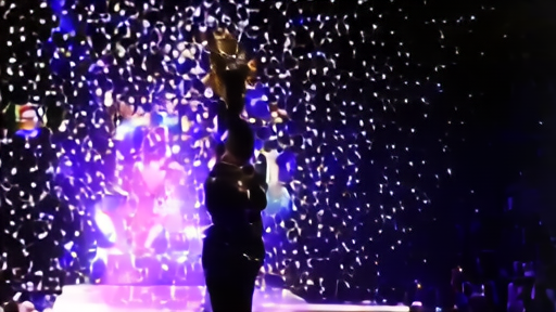 Roman Reigns standing alone in the ring at Allegiant Stadium with the World Heavyweight Championship raised over his head, confetti in the air, shadowed crowd beyond.