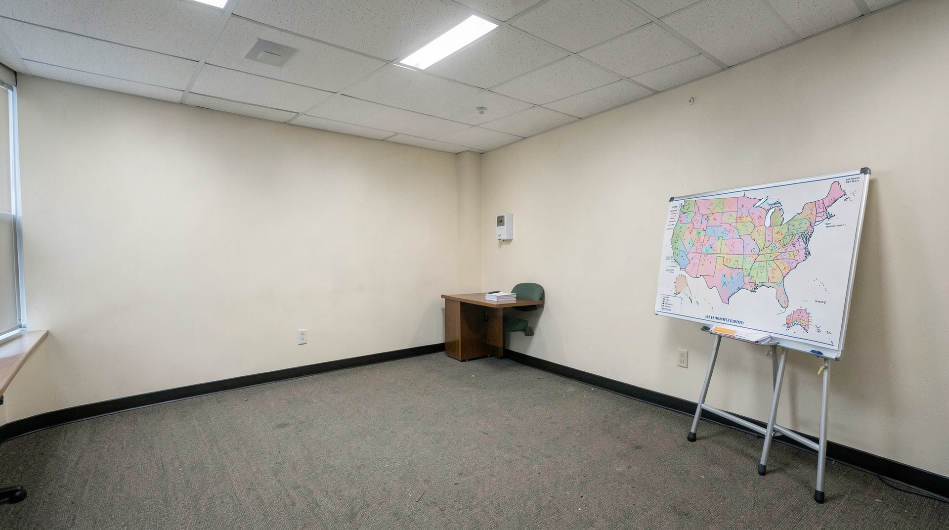 The HHS Humphrey Building press briefing room empty at midday, a measles-outbreak US map printed on an A-frame presentation board leaning against a far wall, no speaker.
