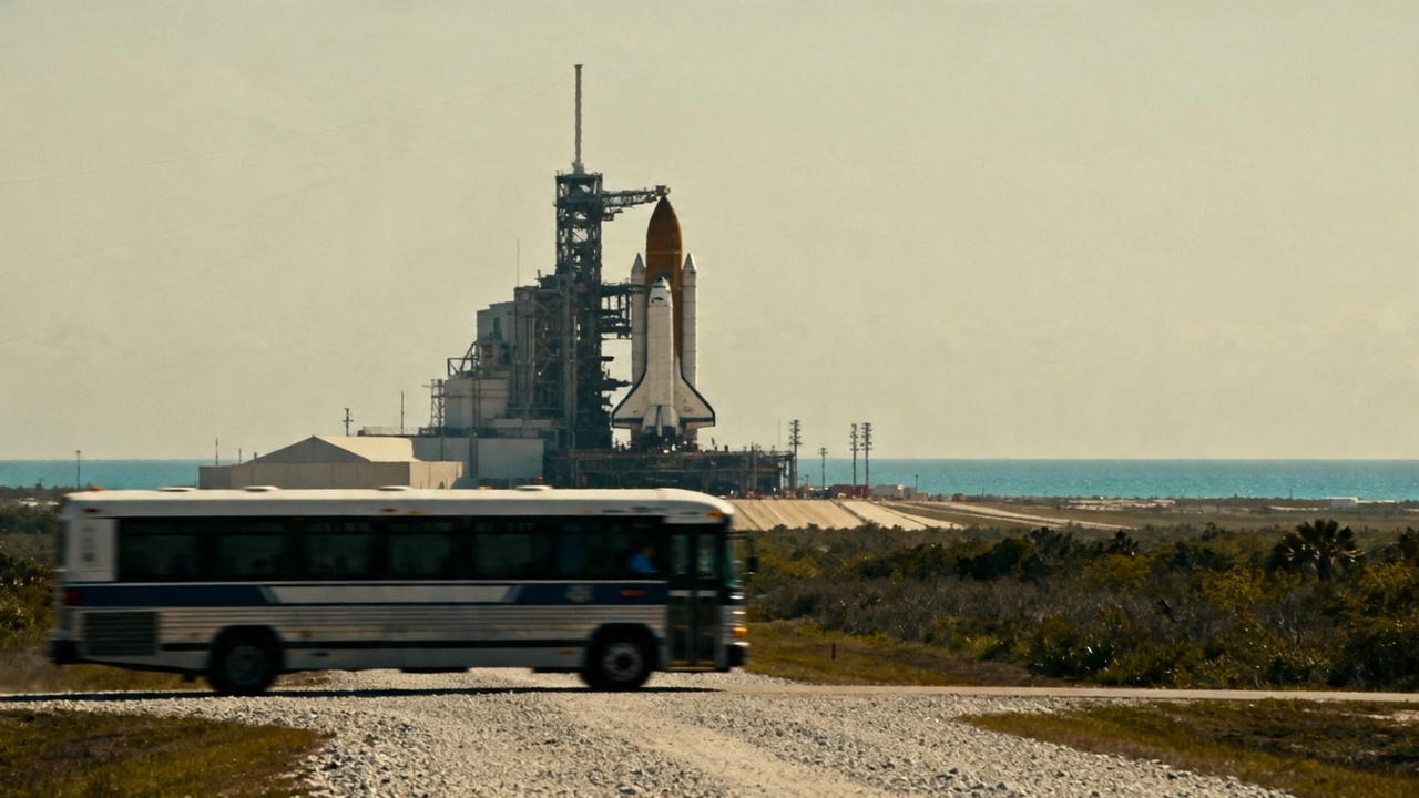 SpaceX Starbase complex in Boca Chica, Texas, with rocket factory in the distance and a shuttle bus bringing analysts from a staging lot