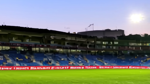 Turf Moor stadium at dusk on a cool April evening, floodlights on, the away-end tunnel visible from the stand, a Burnley claret-and-blue corner flag in foreground and the Lancashire hills behind the West Stand.