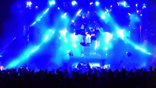 Coachella main stage at night with dense crowd silhouetted against pyrotechnics during Karol G's closing set.