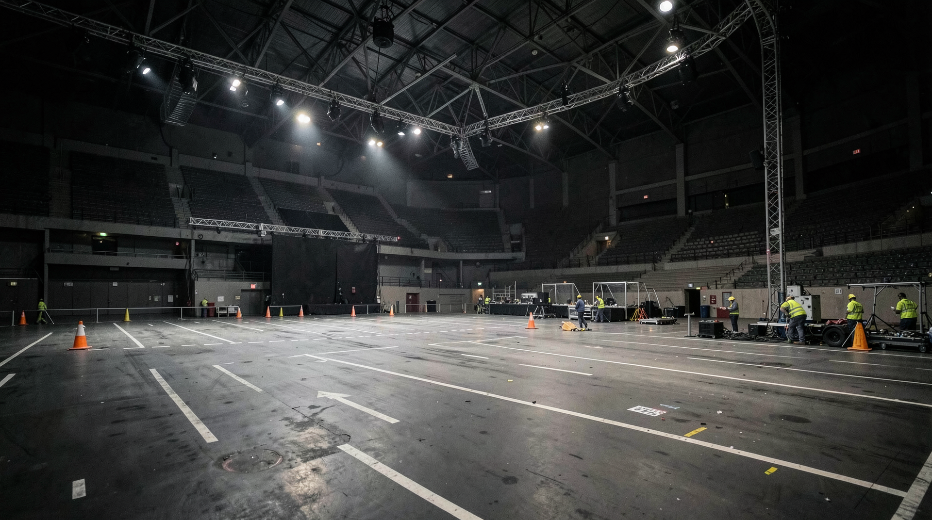 Empty arena floor with stacked road cases and dark stage lights
