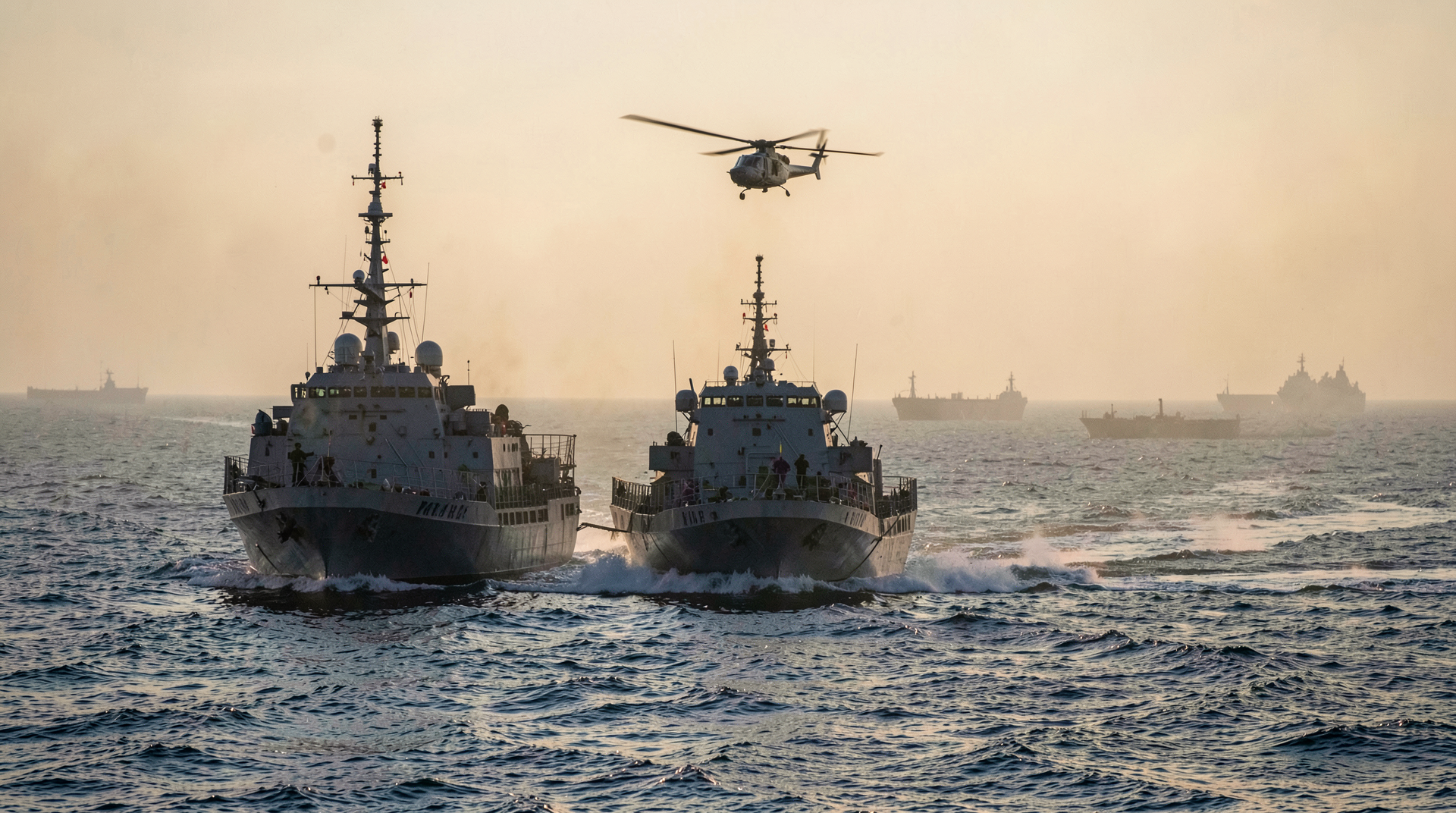 U.S. Navy minesweeper operating at dawn near commercial tankers in the Strait of Hormuz