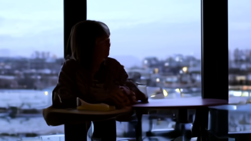 Young adult alone at a cafe table looking at phone