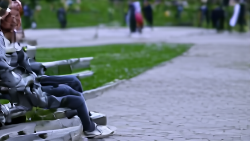 A young adult sitting alone on a public-park bench in early evening, phone face-down beside them, blurred figures in distance.