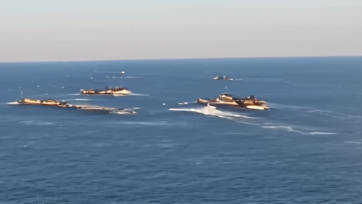 Aerial of three U.S. carriers in the same maritime quadrant with escorts visible at mid-morning