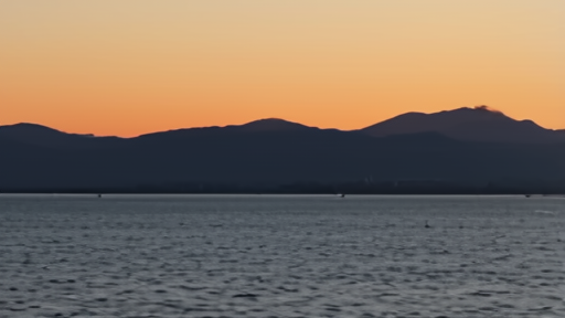 An empty stretch of the Strait of Hormuz at dusk, a single tanker silhouette in the distance, calm water.