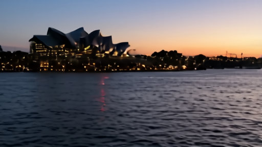 The Sydney Opera House and harbor at dusk with light reflections on the water.