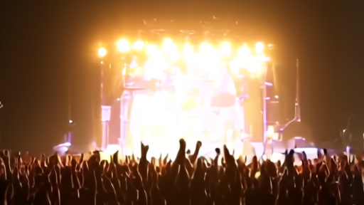 An arena stage with concert lighting on a band performing to a packed crowd.