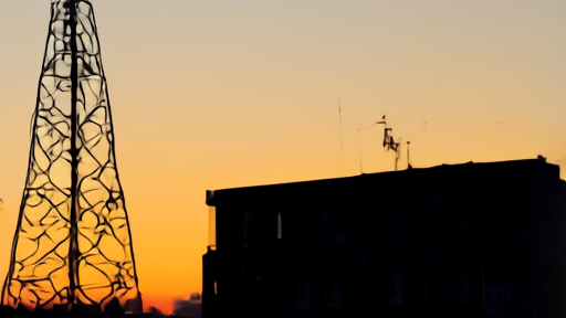 A broadcast transmission tower at dusk with the ABC station call letters faintly visible on a sign at its base.