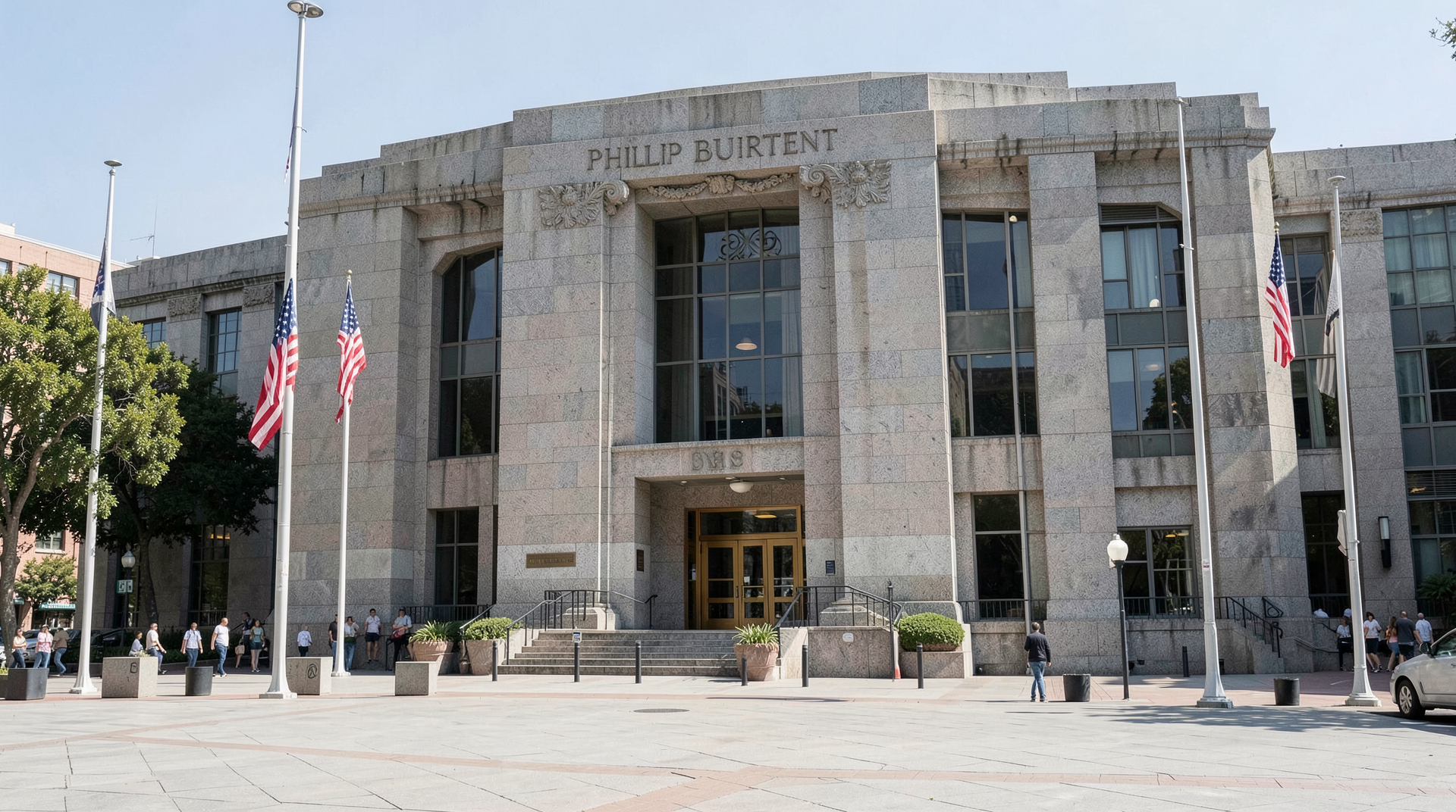 Exterior of the Phillip Burton Federal Building and Courthouse in San Francisco at midday with the granite facade and U.S. flags visible.