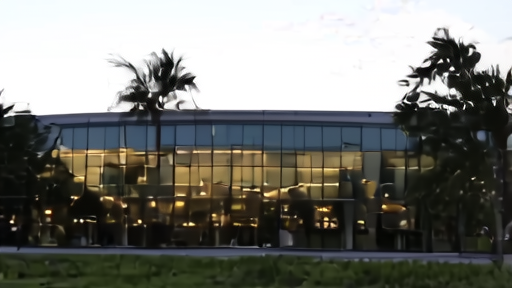 Glass-walled research building of the J. Craig Venter Institute campus in La Jolla under late-afternoon light, with eucalyptus trees in the foreground.
