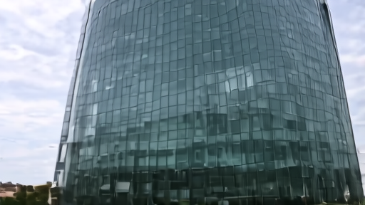 The European Central Bank tower in Frankfurt at midday with the cobblestone plaza below and the EU and German flags visible at the base.