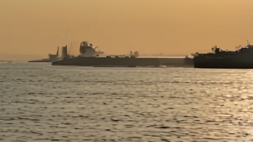 A tanker silhouetted in the Strait of Hormuz at dawn with a small IRGC patrol boat in the foreground.