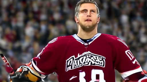 Nathan MacKinnon raising his stick at Ball Arena after a Game Two power-play goal as the home crowd reacts.