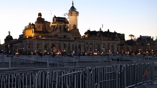 Red Square at dusk on the eve of Victory Day with rehearsal bleachers and barricades in place, a single soldier in dress uniform walking past a bare reviewing stand, St. Basil's Cathedral framed in the background.