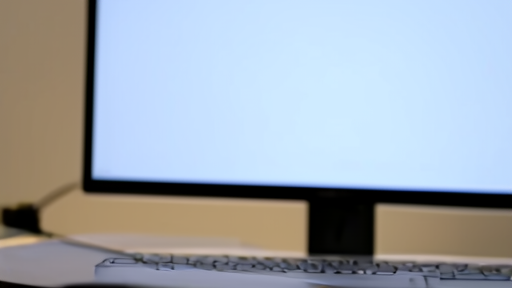A close shot of a corporate laptop keyboard with a monitor in soft background bokeh, a small webcam dot above the screen