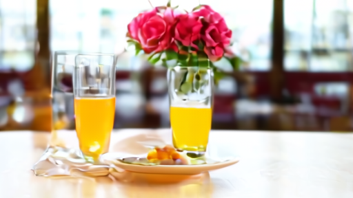 A restaurant brunch table with a small bouquet of pink peonies and two empty mimosa glasses