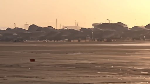 Pakistani military air base at dusk with hangars in silhouette and ground crew at distance