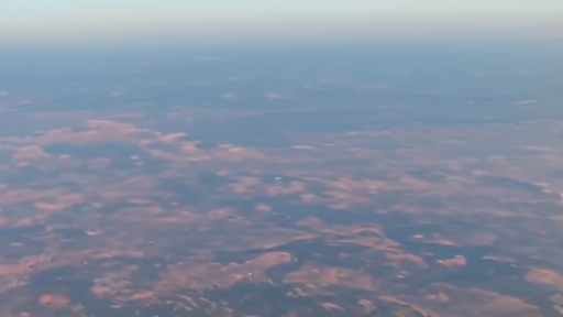 A satellite-style atmospheric haze over the North Pacific Ocean, colored particulate diffusion visible at altitude, no figures.
