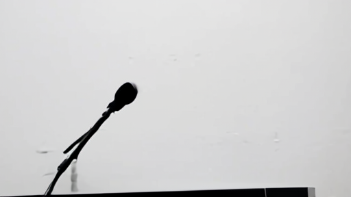 An empty corporate press-conference podium with no nameplate, a single microphone, and a blank wall behind.