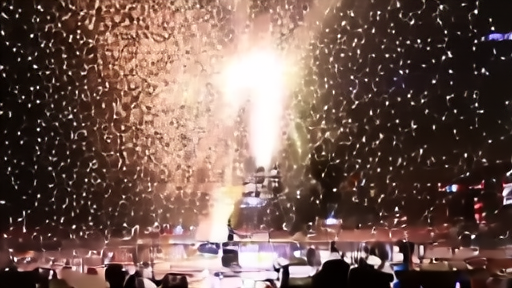 A wide press-row view of an arena floor after the buzzer with confetti mid-fall and a seven-and-a-half-foot silhouette against a scoreboard