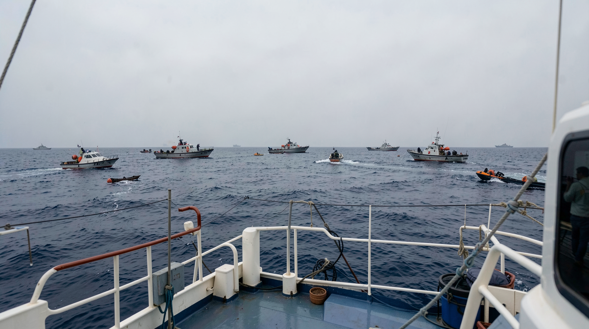 Aid boats on a gray Mediterranean horizon with patrol craft approaching from the side