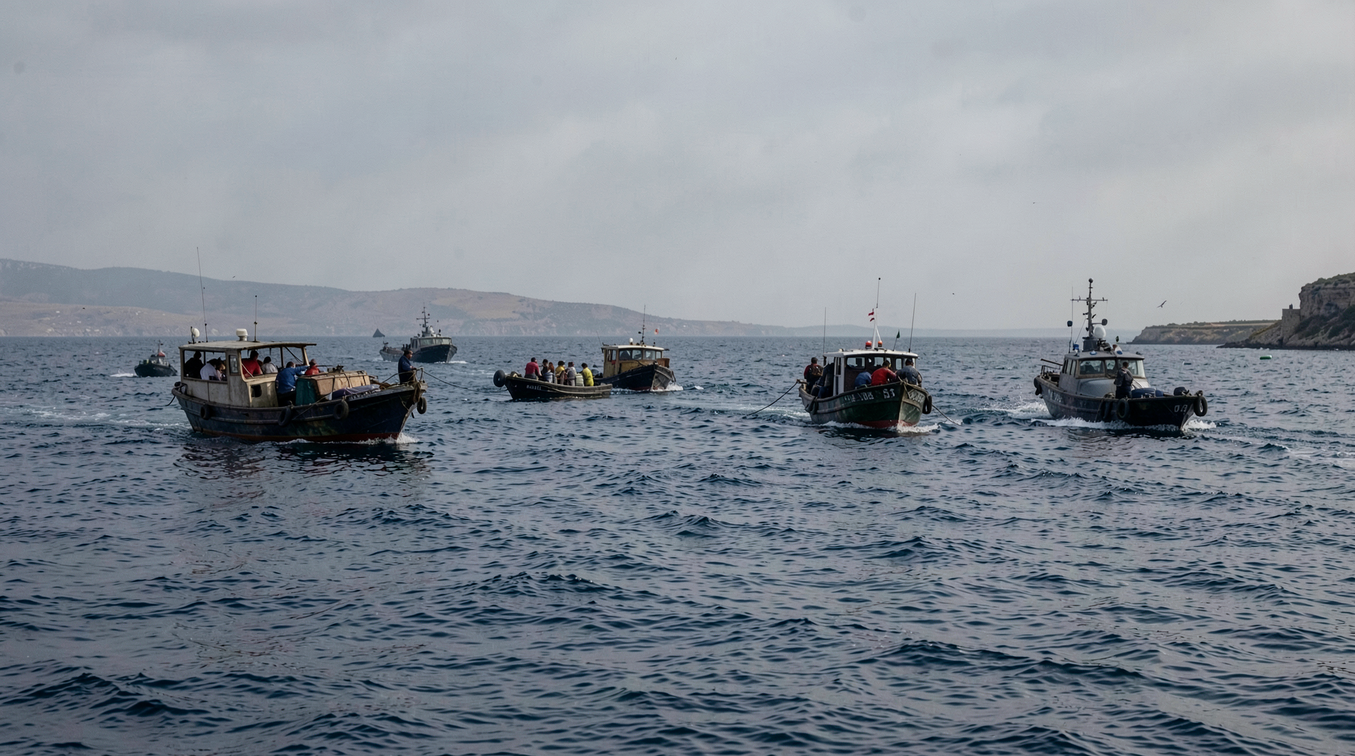 Aid boats on open Mediterranean water near Cyprus as naval speedboats close in under gray light