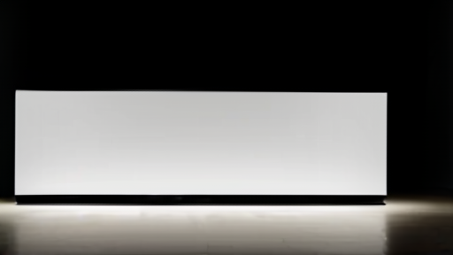 Empty product showroom with a single illuminated podium beneath a blank screen at night.
