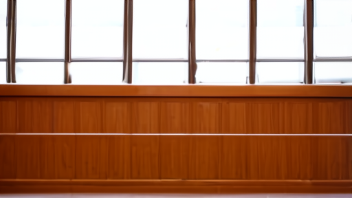 An empty federal courtroom witness chair behind a wooden rail, the seal of the United States District Court visible on the wall, late afternoon