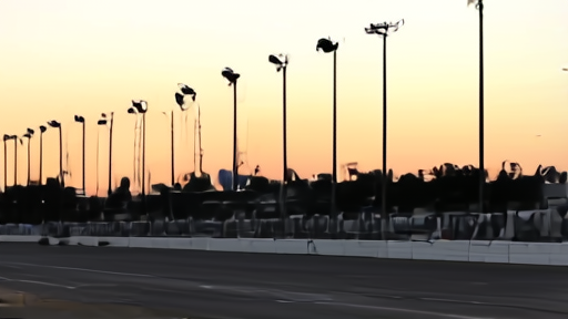 The Indianapolis Motor Speedway pylon at dusk with rows of unlit digital position lights, an empty pit lane in the foreground