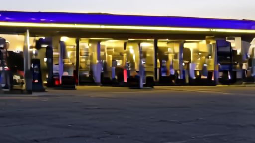 An empty gas station forecourt at dusk with the price sign showing four-dollar pump prices, an American flag flying nearby, no people