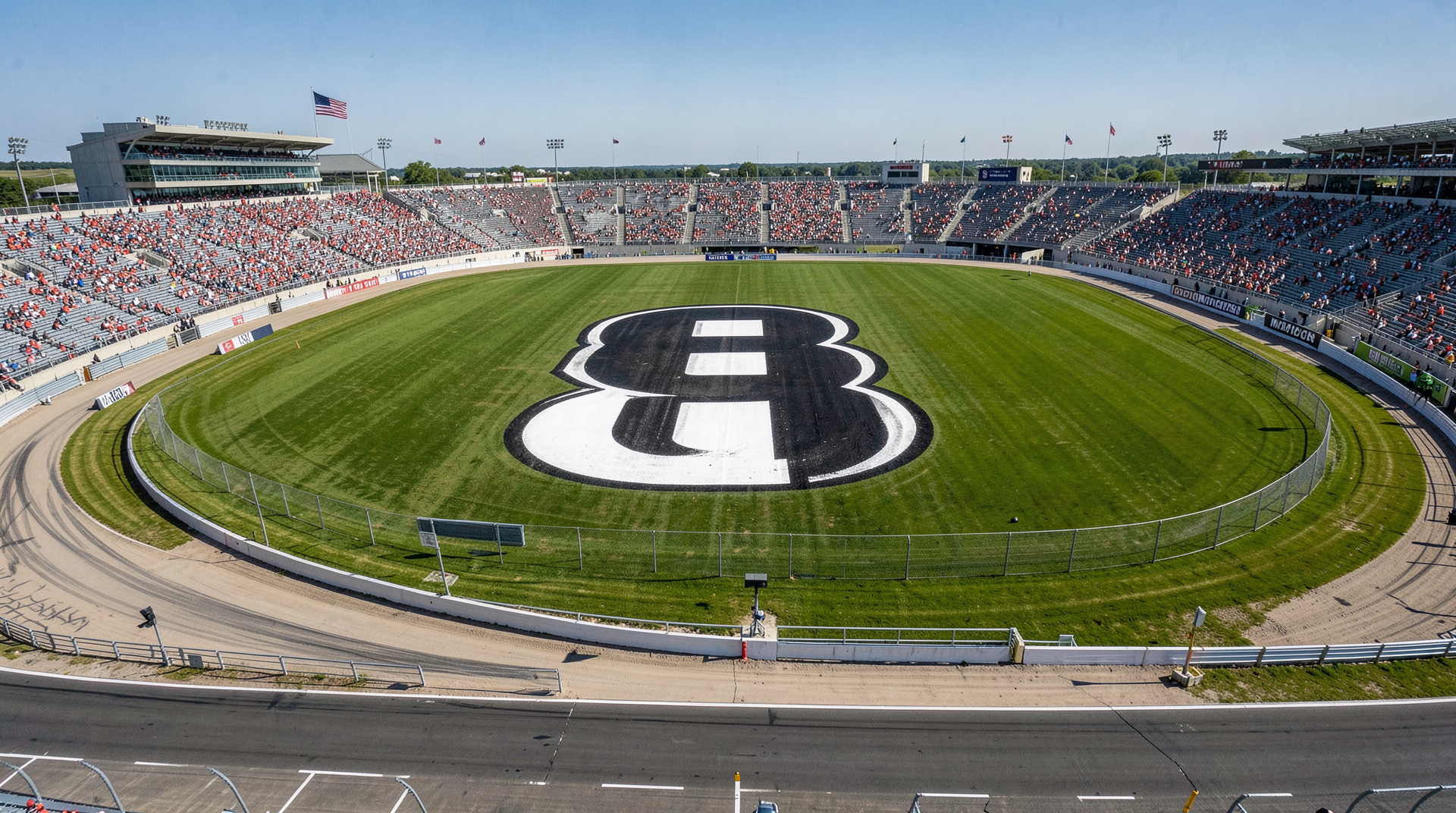An aerial view of Charlotte Motor Speedway's turn one infield grass with a giant black-and-white No. 8 painted into the lawn, grandstands beyond, ahead of the 67th Coca-Cola 600.