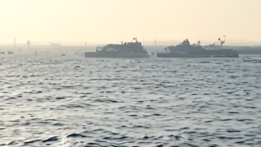 Merchant ships in the Strait of Hormuz watched by military aircraft and patrol boats