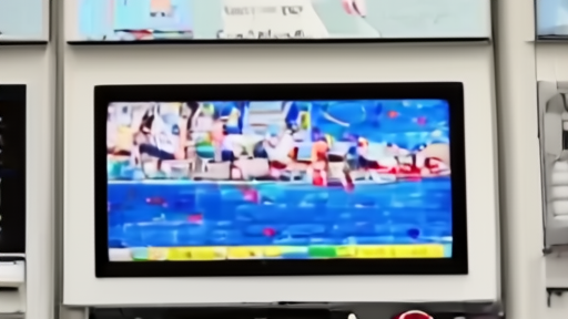 Gas pump display with a Hormuz news broadcast blurred behind it